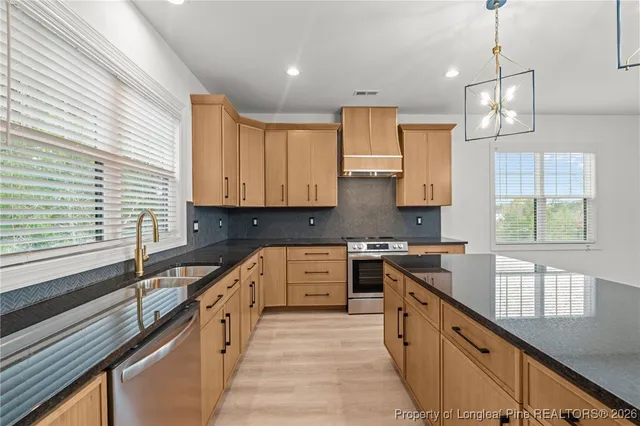 a large kitchen with stainless steel appliances granite countertop a stove a sink and a refrigerator