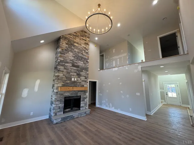 an empty room with wooden floor fireplace and windows