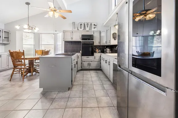 a large white kitchen with cabinets a sink a stove a dining table and chairs