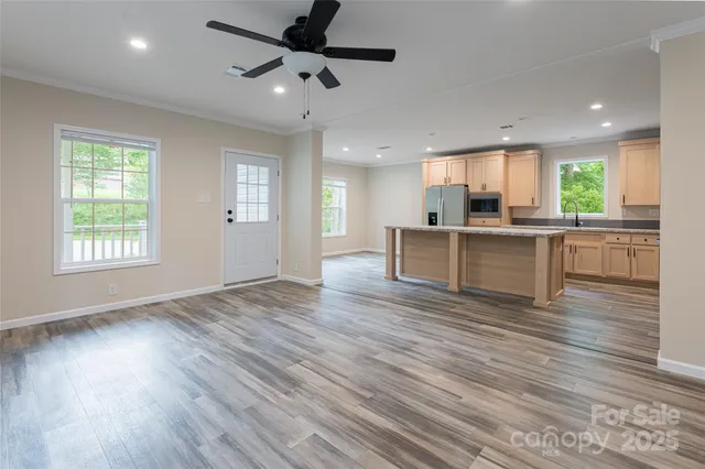 an open kitchen with kitchen island wooden floors and stainless steel appliances