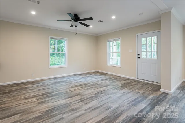 an empty room with wooden floor and windows