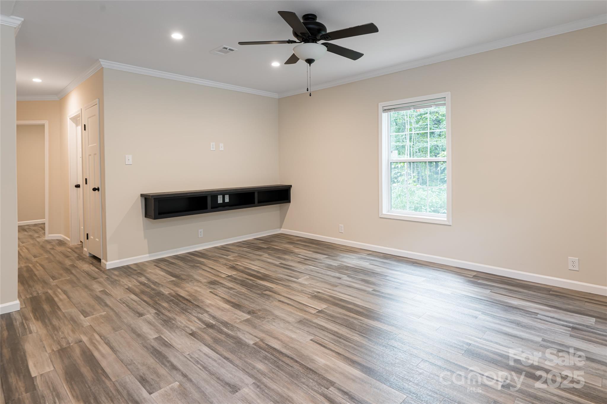 321 Flat Creek Road Black Mountain, NC 28711 - Photo 10 of 44 an empty room with wooden floor ceiling fan and windows