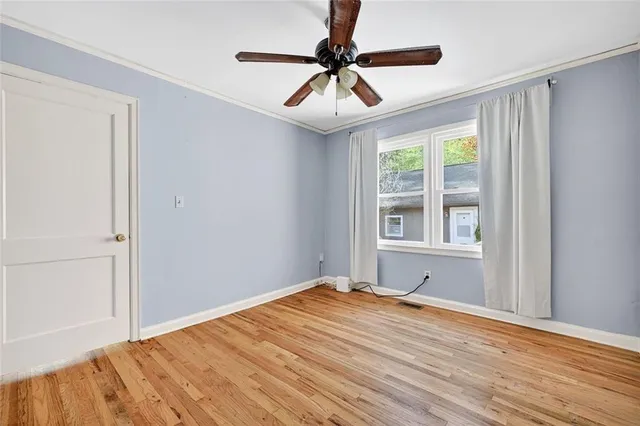 a view of empty room with wooden floor and fan