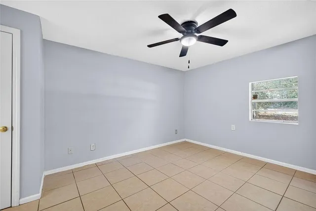 an empty room with ceiling fan and window