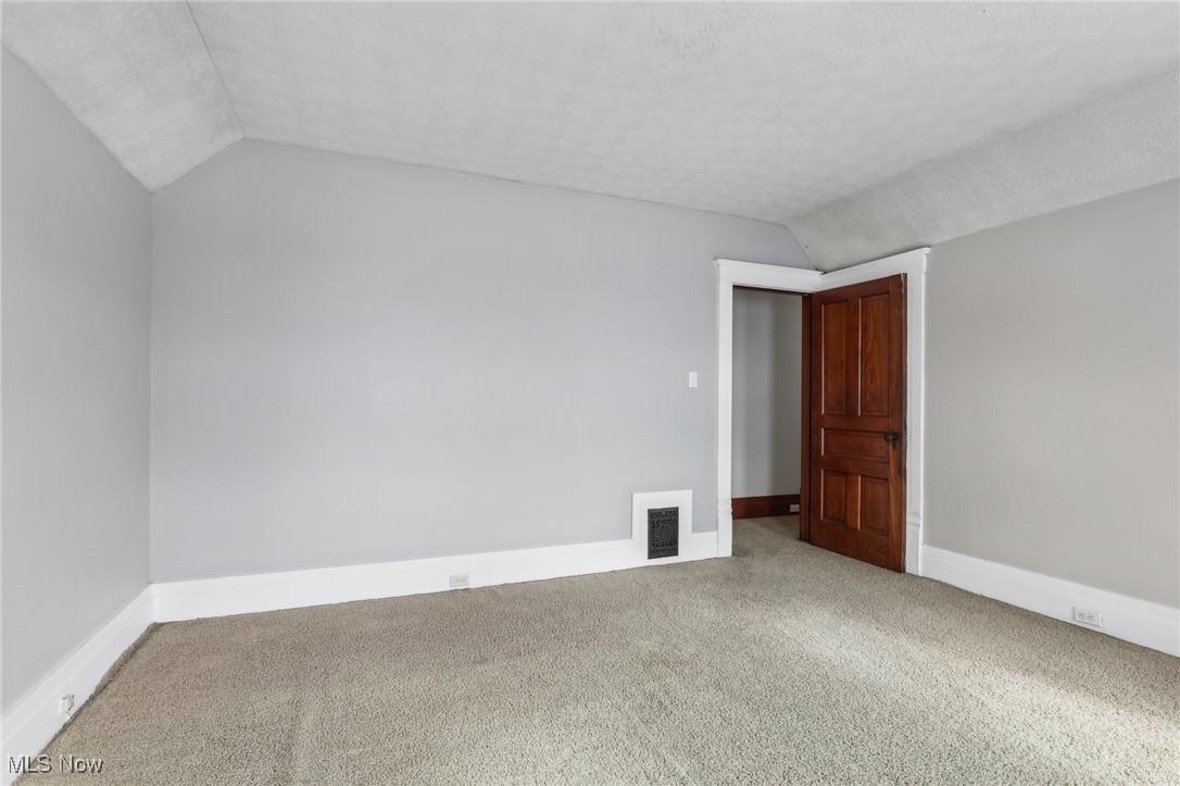 73 East York Street Akron, OH 44310 - Photo 24 of 36 Carpeted empty room featuring vaulted ceiling and a textured ceiling