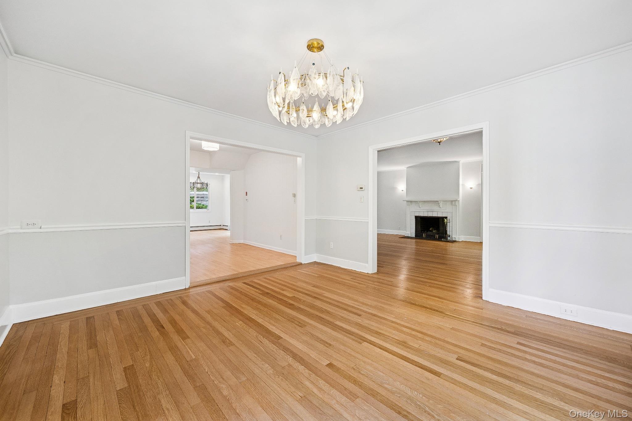 10 River Road Scarsdale, NY 10583 - Photo 6 of 20 Dinning room featuring light wood-style flooring, a chandelier, a fireplace, and ornamental molding