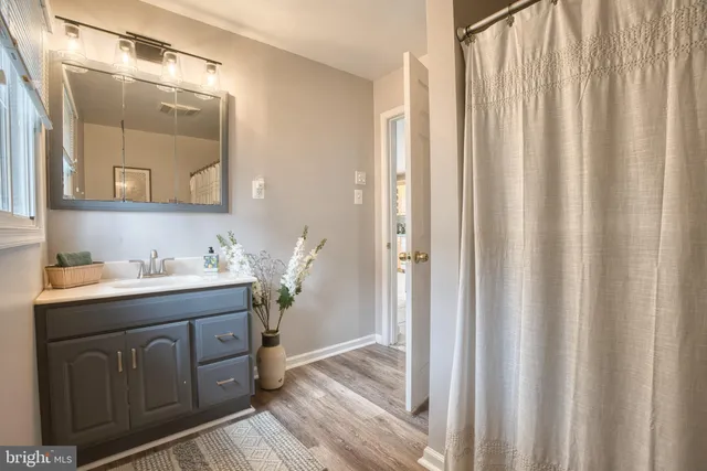a view of a hallway with wooden floor and a bathroom