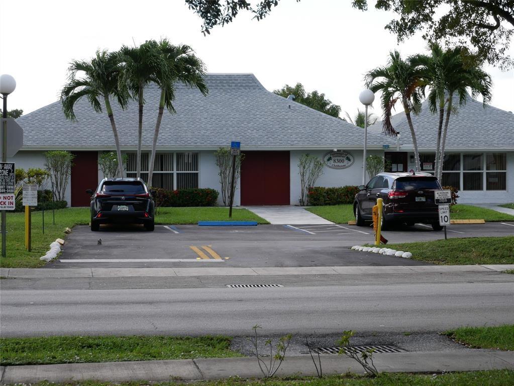 8305 Northwest 61st Street, Unit 203 Tamarac, FL 33321 - Photo 10 of 13 a front view of a house with a garden and trees