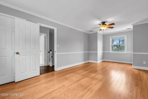 a view of an empty room with a window and wooden floor