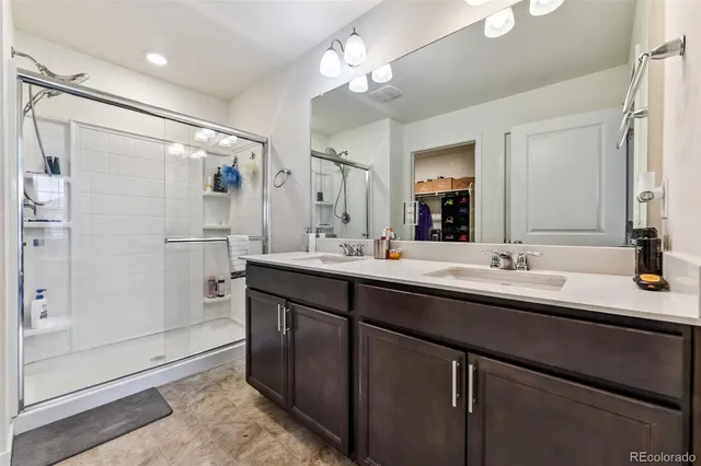 a bathroom with a double vanity sink mirror and shower