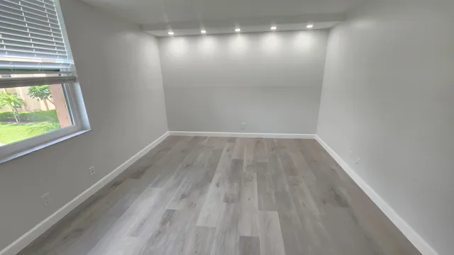 a view of empty room with wooden floor and fan