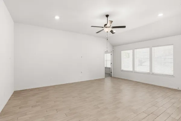 an empty room with chandelier fan and windows