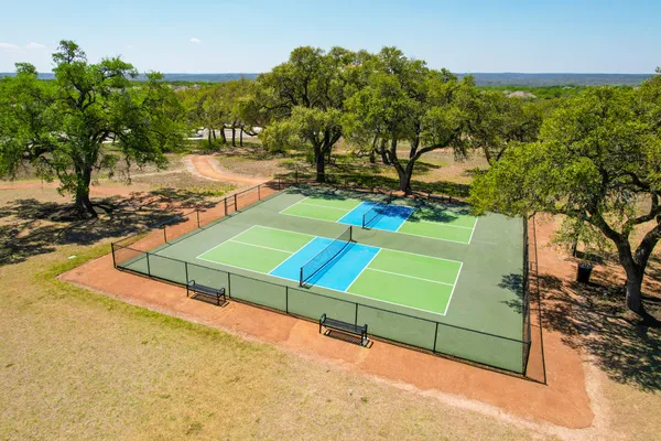 a view of a tennis ground with large trees