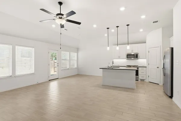 a kitchen with kitchen island a counter top space appliances and a ceiling fan