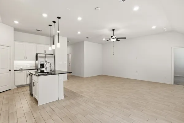 a kitchen with stainless steel appliances a stove a refrigerator and white cabinets with wooden floor