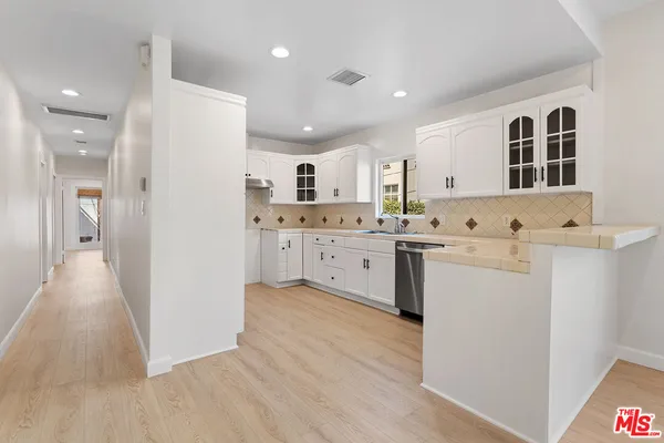 a kitchen with a sink a stove a refrigerator and white cabinets
