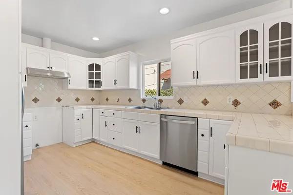 a kitchen with granite countertop white cabinets white stainless steel appliances with a sink and dishwasher