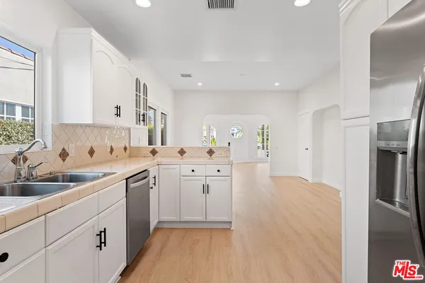 a kitchen with white cabinets sink and stainless steel appliances