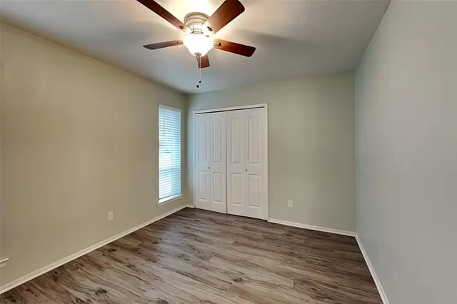 an empty room with wooden floor chandelier fan and closet area with wooden floor