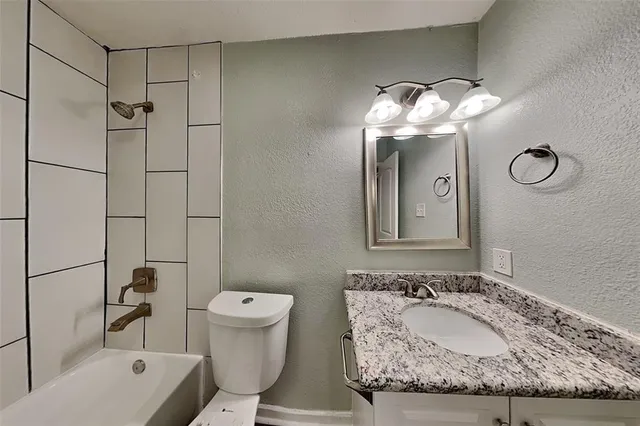 a bathroom with a granite countertop sink mirror and toilet