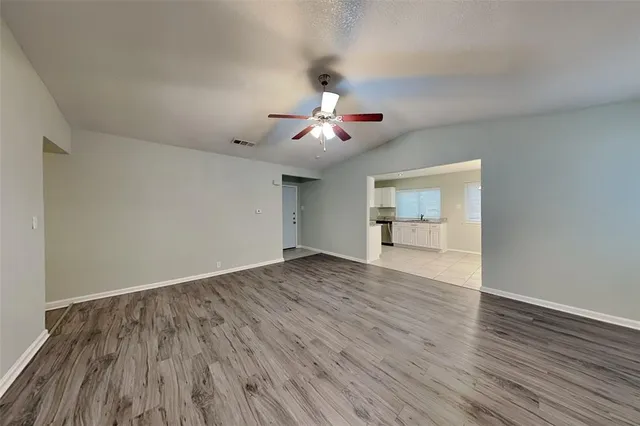 a view of an empty room and wooden floor chandelier fan