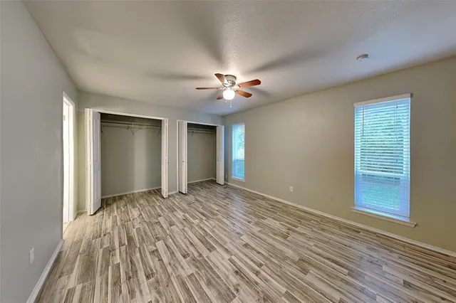a view of empty room with wooden floor and fan