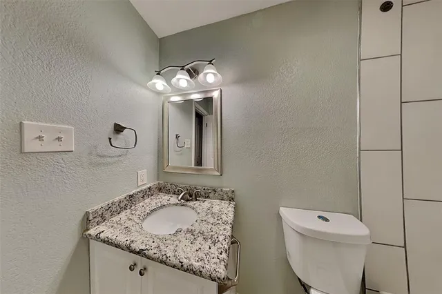 a bathroom with a granite countertop sink a toilet and a mirror