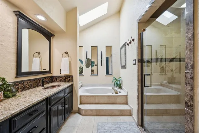 a spacious bathroom with a granite countertop tub a double vanity sink and a large mirror