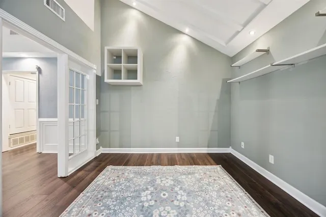 a view of an empty room with wooden floor and a ceiling fan