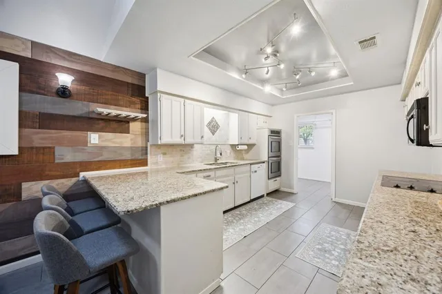 a large white kitchen with a large window and stainless steel appliances