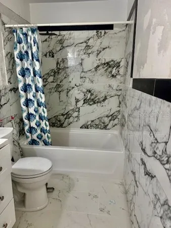 a bathroom with a toilet and a shower curtain