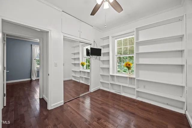a view of an empty room with a window and wooden floor