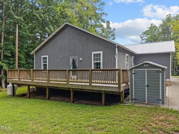 a view of a house with a backyard and a wooden deck