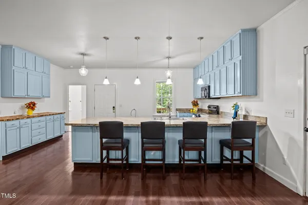 a kitchen with a dining table chairs and wooden floor