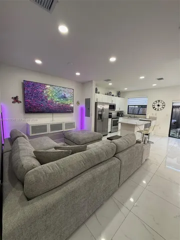 a living room with furniture and a view of kitchen