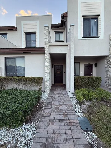 a view of a house with a yard and potted plants