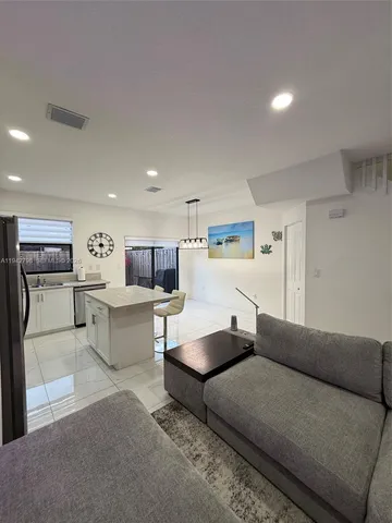 a living room with furniture and kitchen view