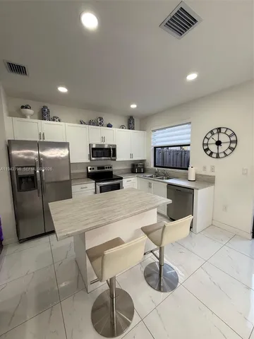 a kitchen with stainless steel appliances kitchen island granite countertop a sink a stove a microwave a counter top and cabinets