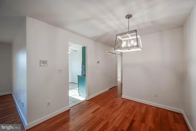 a view of a hallway with wooden floor and chandelier