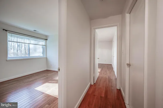 a view of a hallway with wooden floor and a bathroom