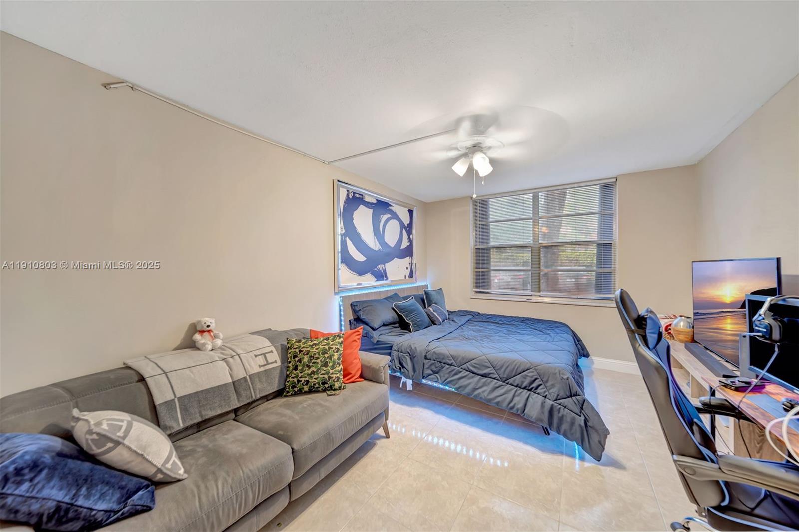 6700 Cypress Road, Unit 105 Plantation, FL 33317 - Photo 18 of 28 a spacious bedroom with a bed a couch and a chandelier