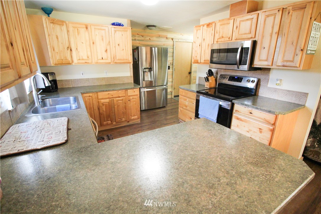 5432 188th Avenue Southwest Rochester, WA 98579 - Photo 7 of 31 a kitchen with stainless steel appliances a stove a refrigerator a sink a stove top oven with wooden floor