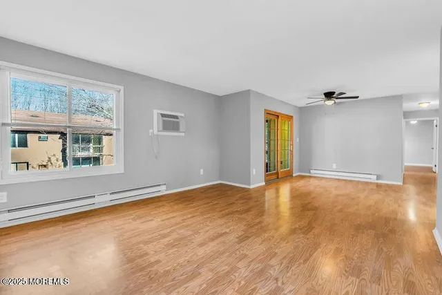 a view of an empty room with a window and wooden floor