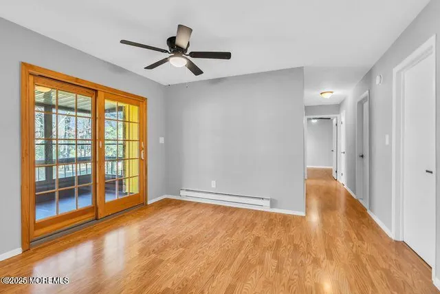 a view of empty room with wooden floor and fan