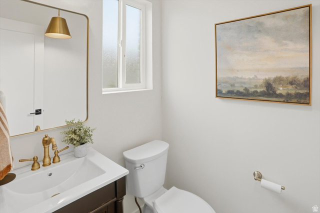 8760 Rustler Road Cottonwood Heights, UT 84093 - Photo 21 of 57 Vanity with white countertop and integrated sink, featuring a gold-toned faucet and a framed mirror