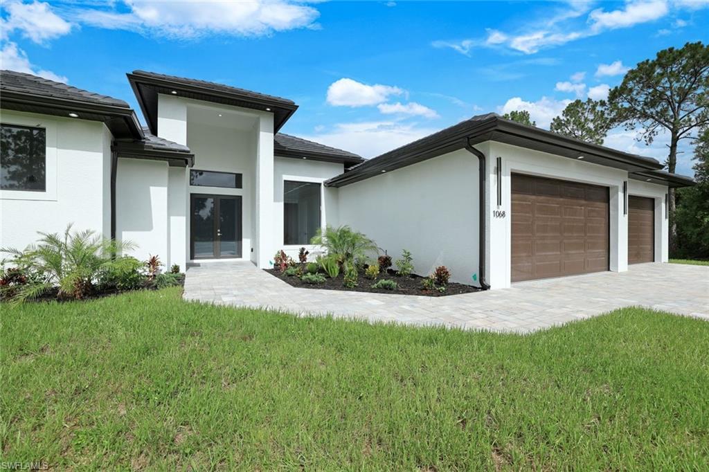 1068 16th Street Northeast Naples, FL 34120 - Photo 1 of 35 a front view of a house with a yard and garage
