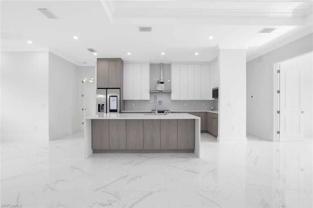 1068 16th Street Northeast Naples, FL 34120 - Photo 5 of 35 a large kitchen with stainless steel appliances granite countertop a stove a sink a refrigerator and white cabinets