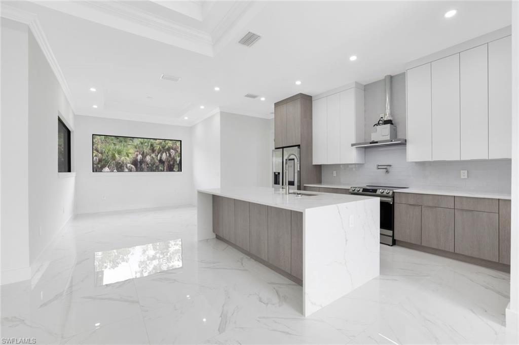 1068 16th Street Northeast Naples, FL 34120 - Photo 6 of 35 a large white kitchen with granite countertop a sink a window and a stainless steel appliances