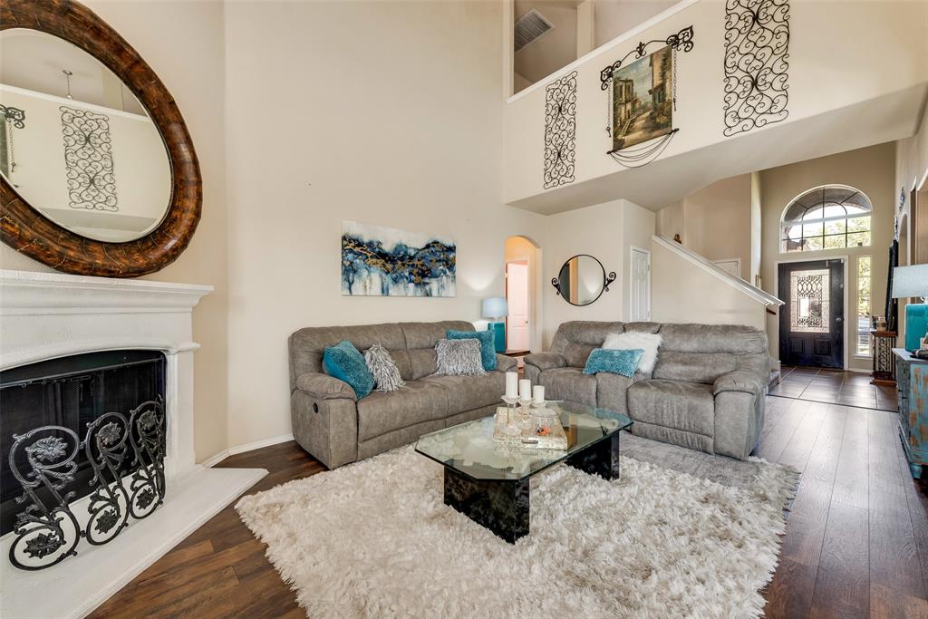 12628 Joplin Drive Frisco, TX 75036 - Photo 1 of 28 Living room featuring visible vents, a fireplace with raised hearth, arched walkways, hardwood / wood-style floors, and a high ceiling