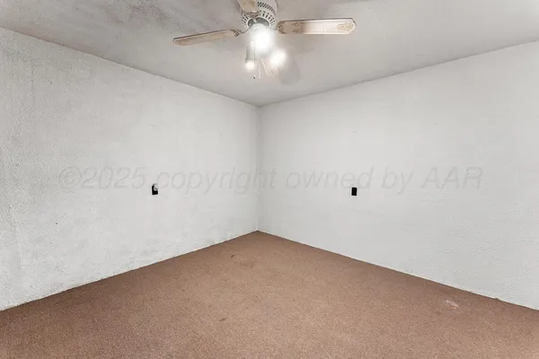 an empty room with a chandelier fan and windows